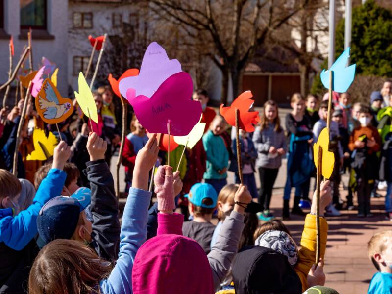 Kinder die selbstgeabsteltete Friedenstauben hochhalten und in einem Kreis stehen 