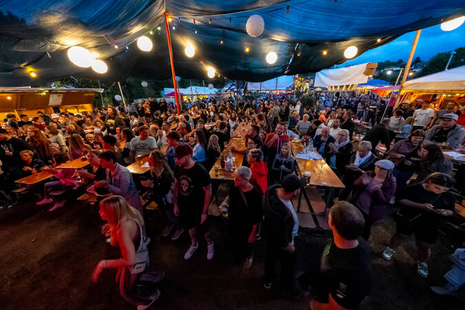 Das Brigachtaler Dorffest bei Dämmerung mit zahlreichen Besucherinnen und Besuchern, die zwischen Biertischen stehen und sitzen, unter einem großen, mit Lichterketten beleuchteten Zelt.