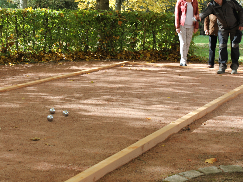 Menschen die Boule-Spielen, drei Kugeln liegen auf dem Feld.