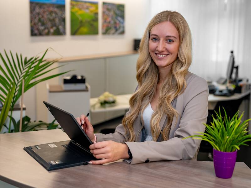 Chiara Schmidt steht an einer Theke im Büro und lächelt in die Kamera