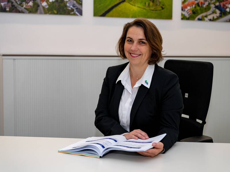 Martina Enderlein sitzt an einem Schreibtisch im Büro und lächelt in die Kamera