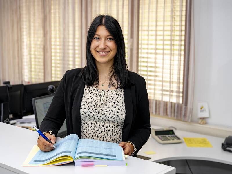 Alisa Tadic steht in einem Büro und lächelt in die Kamera