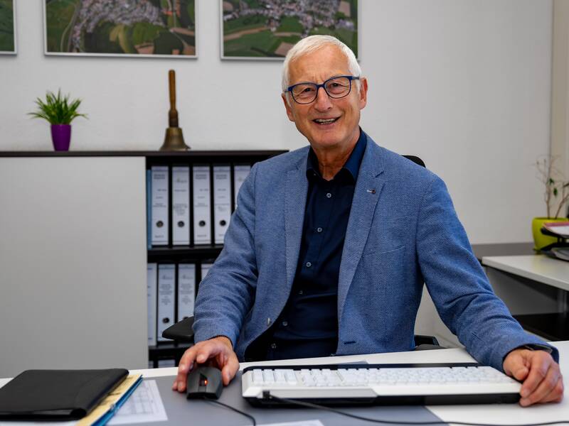 Martin Weißhaar sitzt an einem Schreibtisch im Büro und lächelt in die Kamera