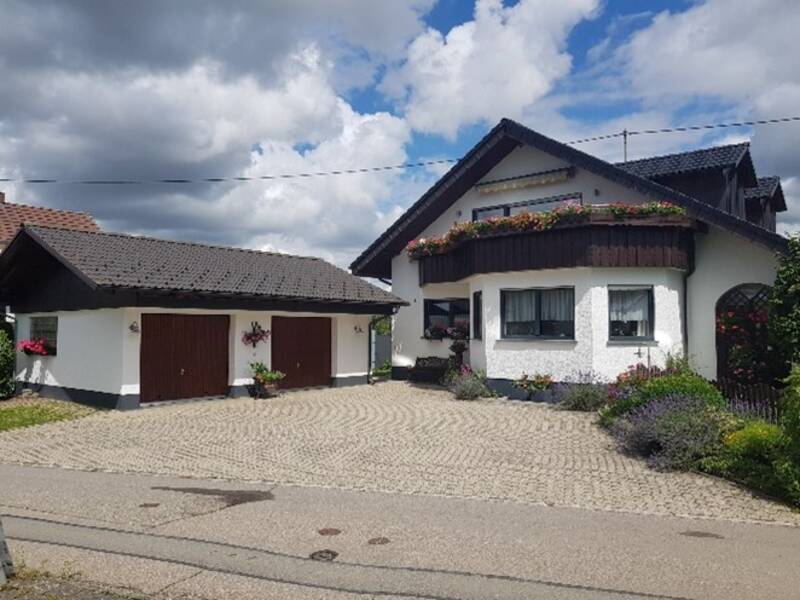 Ein Haus mit Einfahrung unter blauem Himmel.