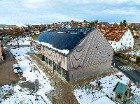 Dorfhaus Brigachtal. Auf dem Dach sind Photovoltaikplatten. Die Fasade ist aus Holz. Um das Haus liegt Schnee.